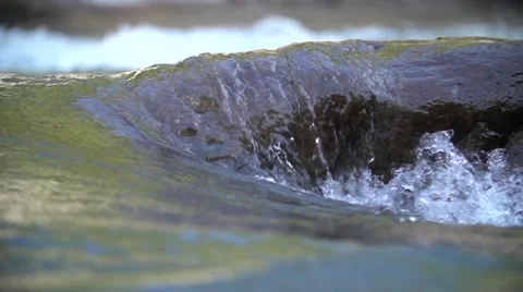 Water in the beautiful mountain river flows round a big stone in slowmotion Video stock 55525610