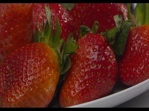 Water is being poured on strawberries on a white plate, medium shot, slow motion Stock Footage 74199999