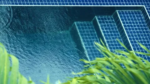 Water in the blue pool splashes from drops of heavy tropical rain. View from top Stock Footage 305669929