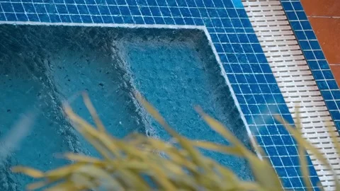 Water in the blue pool splashes from drops of heavy tropical rain. View from top Stock Footage 318685679