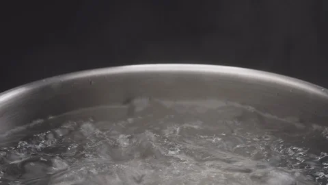 Boil water in a pot on dark background, Stock Video