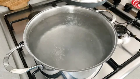 Water boiling inside a steel pot for cooking pasta. Modern home kitchen of a Stock Footage 128669780
