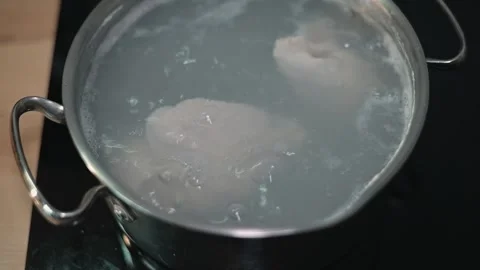 Water is boiling in a pot as a piece of chicken is placed inside. The process 库存影片 338301345