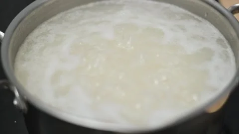 Water is boiling in a pot on a stove in a kitchen. The focus is on the bubbling Stock-Footage 338298552