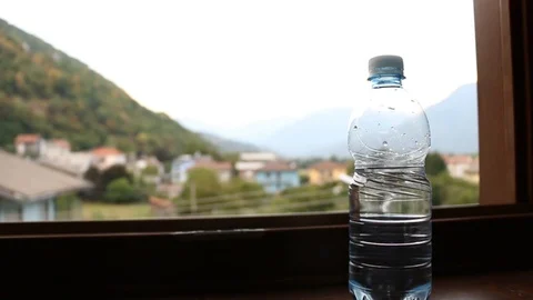 Water bottle on a window with mountains background Stock Footage 93327638