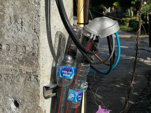 Water bottles used as makeshift electrical wire protection on a utility pol.. Stock Photos