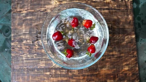 Water bowl captures the dynamic splash of fresh strawberries as they dropped in Stock-Footage 321353591