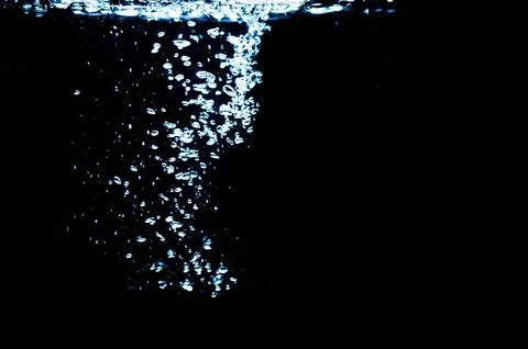 Water bubbles isolated on black background, close up view. Rippling liquid su Stock Photos
