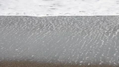 Water bubbles on sandy beach with white frothy sea wave background Stock Footage 303256499