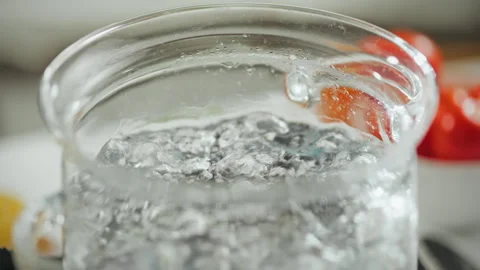 Water bubbling in a clear glass container with fresh vegetables on a kitchen Stock Footage 295129789