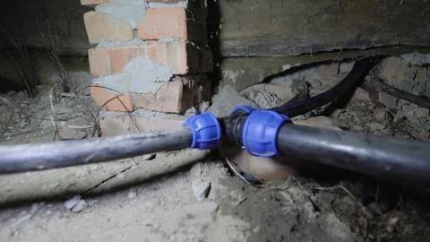 Water bursting from a broken pipe joint in a dark, dirty basement, flooding the Stock Footage 319918810