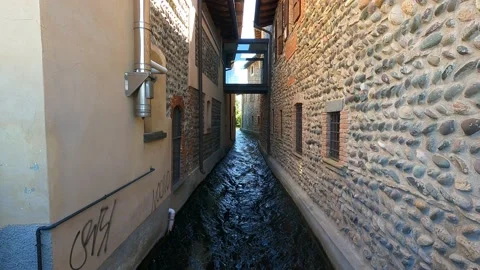 The water of a canal flows fast between the walls of the houses Stock Footage 154912275