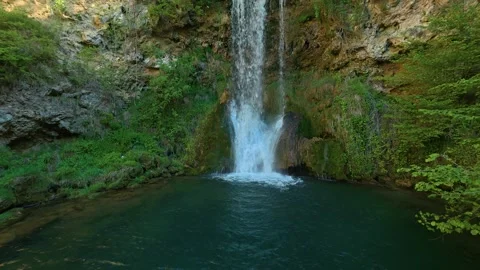 Water cascades down a mossy cliff into a calm, deep pool. Veliki Buk, Serbia. Stock Footage 336888987