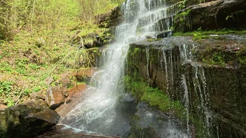 Water cascades down mossy, rugged rocks. Slowmotion. Tupavica Waterfall Stockbeeldmateriaal 335535969