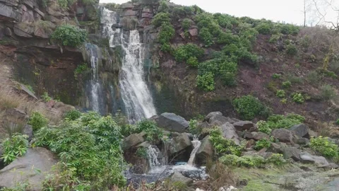 Water cascades down rocky cliff face 스톡 동영상 342941017