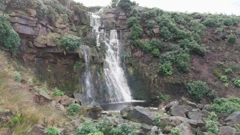 Water cascades down a rocky cliffside with greenery 库存影片 342926247