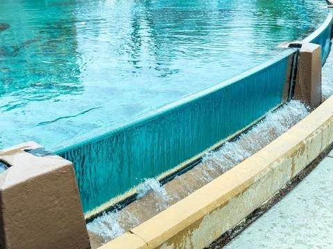 Water cascades down a wall into a pool, creating ripples in the clear water.  Foto stock