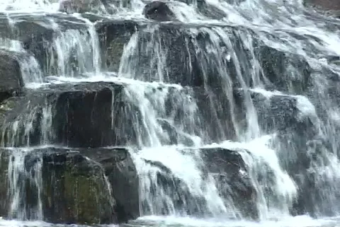 Water cascading down over dark rocks top to bottom Stock Footage 192549833