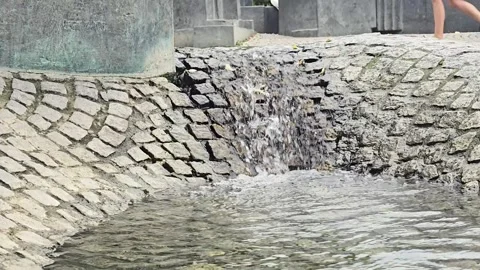 Water cascading down a stone structure in a public park Stock Footage 345097500
