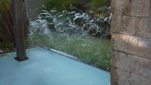 Water cascading down a stone wall into a swimming pool Stock Footage 346093669