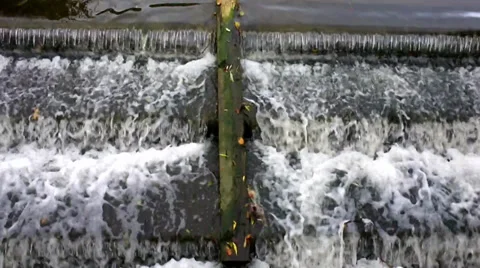 Water cascading down a weir past a wooden plank Stock Footage 32395569