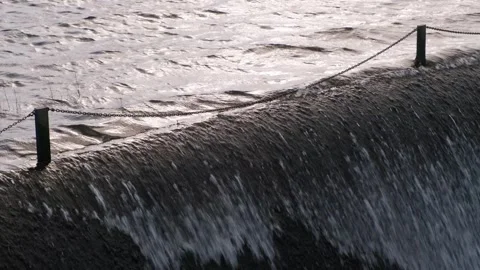 Water cascading over a dam during the golden hour at sunset Stock Footage 306393011