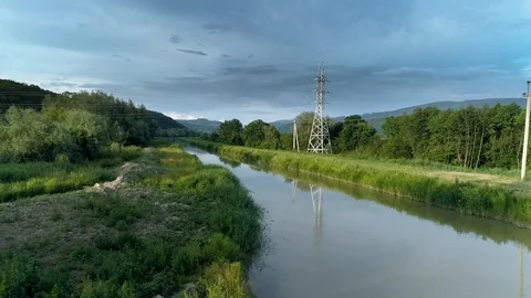 Water channel is a tributary of a river with power lines across. Stock Footage 109308932