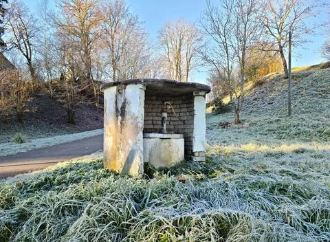 Water column protected by brick wall on hillside overgrown with grass silve.. Stock Photos