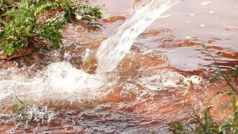 Water coming out of a plastic pipe and falling into a pit filled with water Stock Footage 150716455
