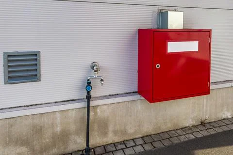 Water connection hydrant next to a red utility box on a building Stock Photos