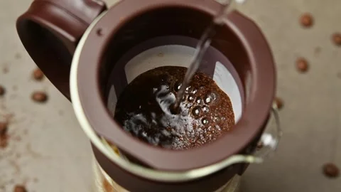 Water continues pouring over coffee grounds in a cold brew filter as bubbles Stock Footage 346743759