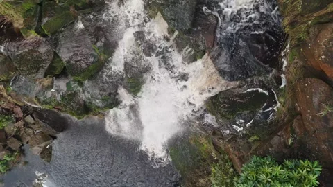 Water crashes over mossy rocks in roaring cascade 库存影片 342930778