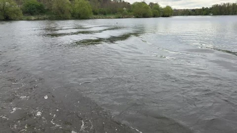 Water current moving causing gentle ripples flowing across wide river channel, Stock Footage 333163786