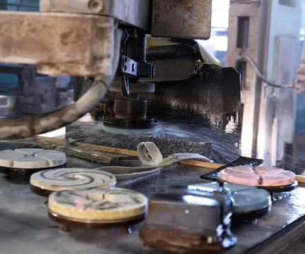 Water cutting process in a workshop creating intricate designs on stone piece Stock Photos