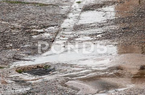 Water damage to road from burst leaking water pipe Stock Photos
