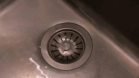 Water drains through stopper from stainless steel kitchen sink, detail Stock Footage 265570098