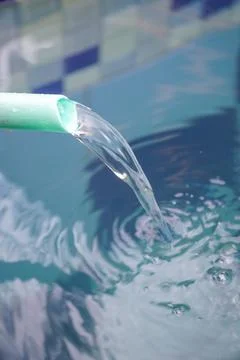 Water dripping down the pool from a plastic hose Stock Photos