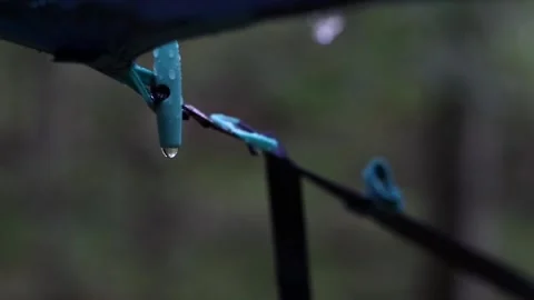 Water dripping from a waterproof blue canopy during rain in the forest Stock Footage 159887991