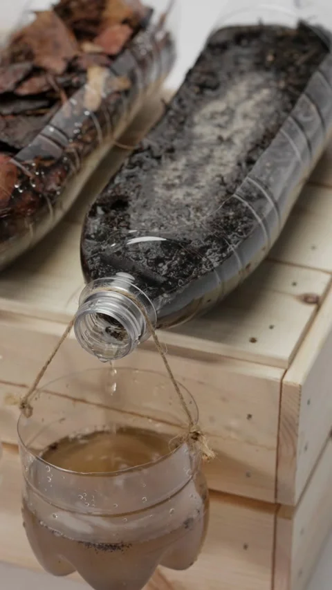 Water drips from recycled plastic bottle into clear container Video stock 331769916
