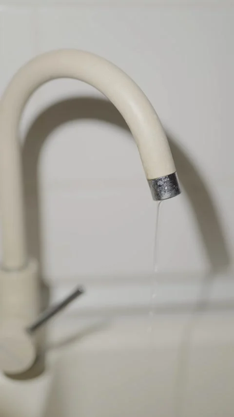 Water drips slowly from a beige kitchen faucet into sink Stock Footage 333527176