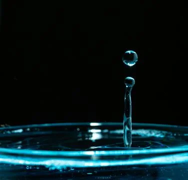 Water drop closeups while drops falling down and splashing into water in Jena Stock Photos