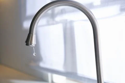 Water drop falling down from tap on blurred background, closeup Stock Photos