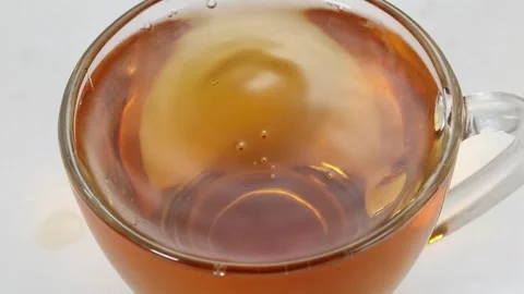 Water Drop Falling into Glass Cup of Black Tea in Slow Motion Stock Footage 342497572