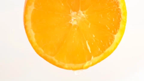 Water drop falling from orange on white background. Orange slice and water .. Stock Footage 273677836