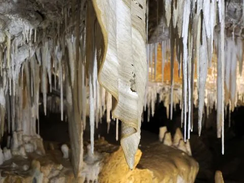 Water drop falling from stalactite inside karst caves carved out by water Stock Photos