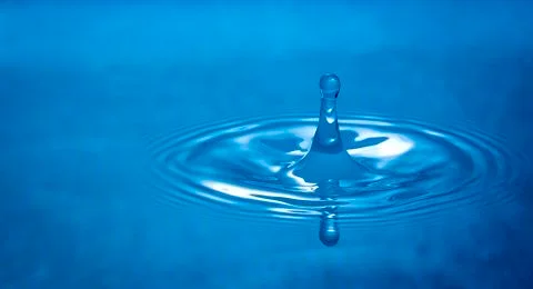Water drop falling into water Stock Photos