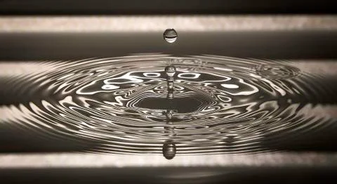 Water drop falling into water Stock Photos