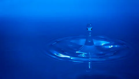 Water drop falling into water Stock Photos