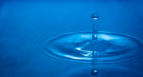 Water drop falling into water Stock Photos