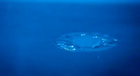 Water drop falling into water Stock Photos